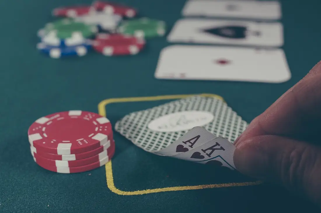 Tangan pemain memegang kartu as dan raja sekop di meja poker